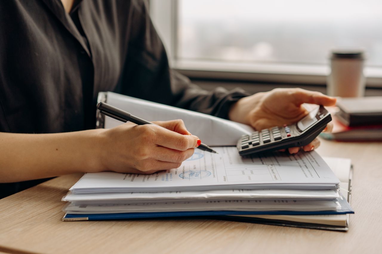 Person reviewing credit report and budgeting documents while considering help from the best debt counsellor for financial relief