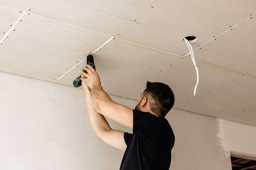 Professional assessing a damaged ceiling during a repair
